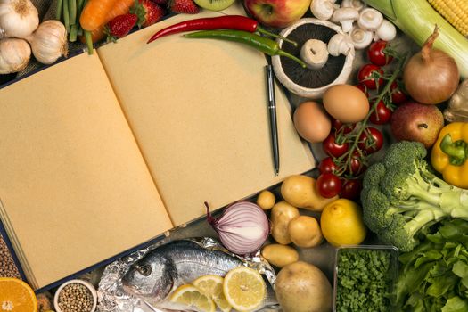 Staple foods - Fruit, Fish and Vegetables with the blank pages of a recipe book - Space for text.