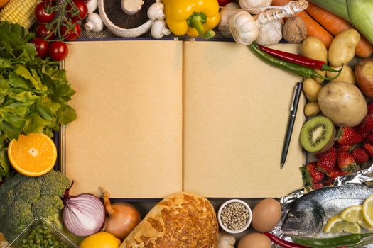 Staple foods - Fruit, Fish, Bread and Vegetables with the blank pages of a recipe book - Space for text.