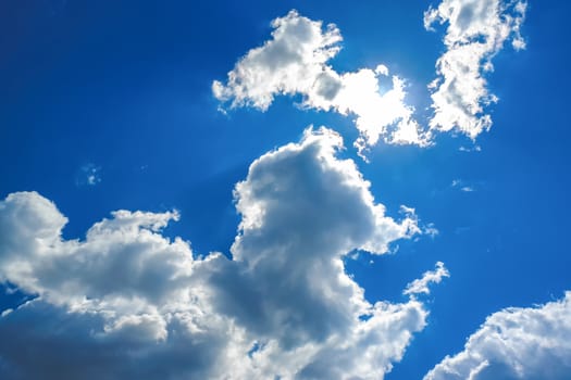 Sun under clouds on blue sky background