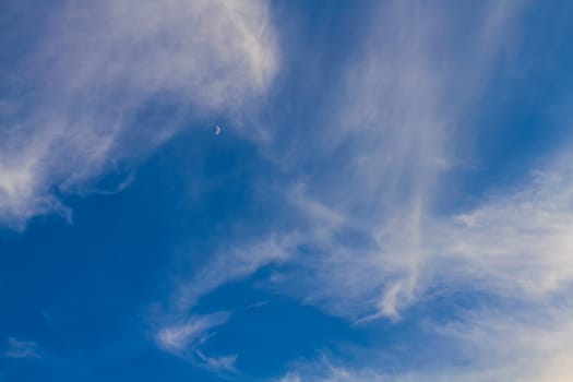 Moon or crescent on blue sky with clouds