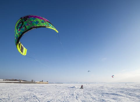 Kite surfer being pulled by his kite across the snow