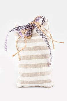 Decorative textile sachet pouch with a ribbon and bow on white background