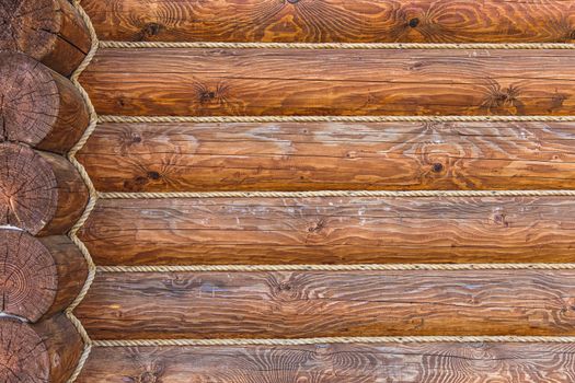 Wooden logs wall with rope of rural house background