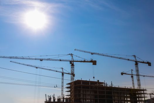 Construction cranes on building site on sky background