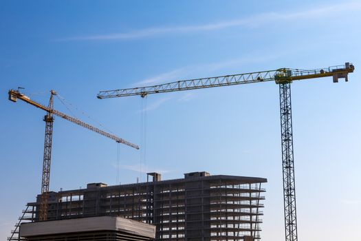 Construction cranes on building site on sky background