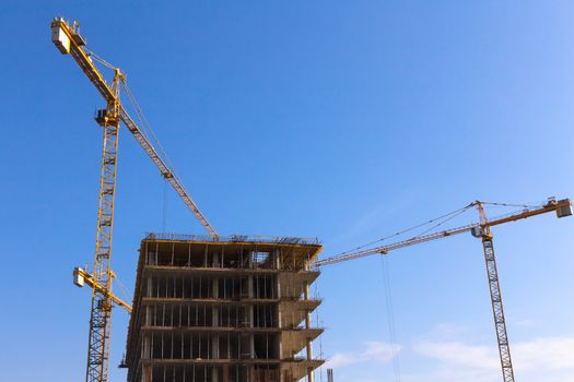 Construction cranes on building site on sky background
