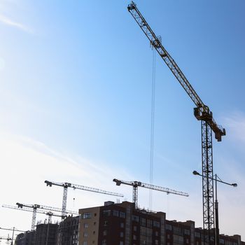 Construction cranes on building site on sky background
