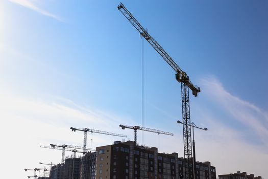 Construction cranes on building site on sky background