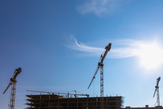 Construction cranes on building site on sky background