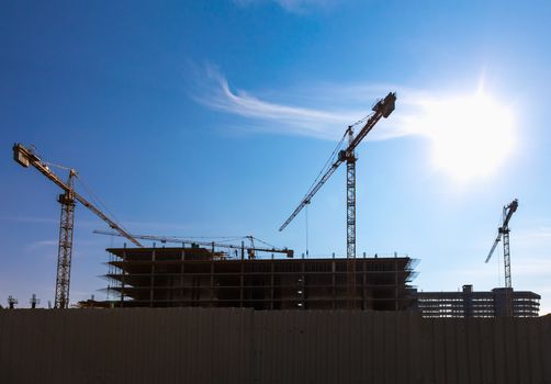 Construction cranes on building site on sky background