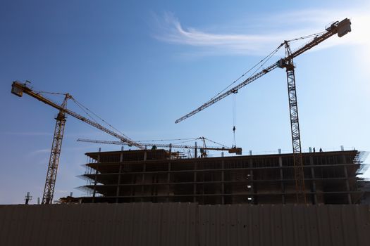 Construction cranes on building site on sky background