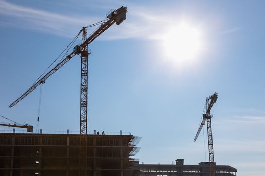 Construction cranes on building site on sky background