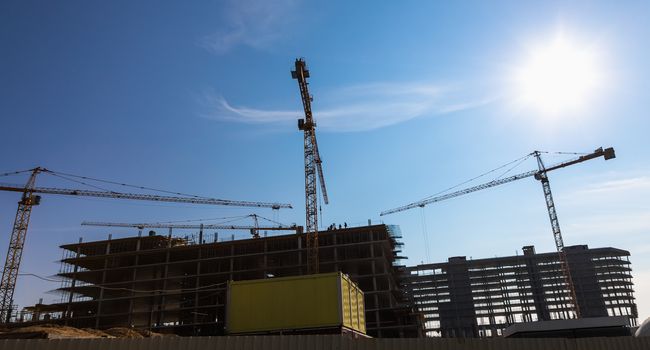 Construction cranes on building site on sky background