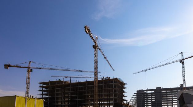 Construction cranes on building site on sky background