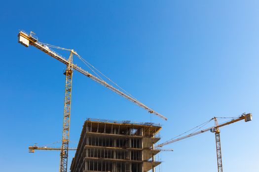 Construction cranes on building site on sky background