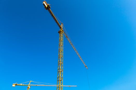 Construction cranes on blue sky background