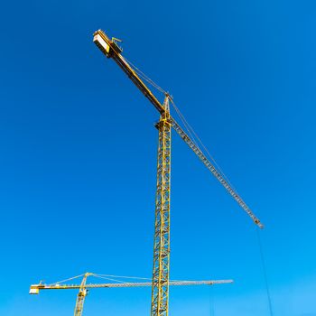 Construction cranes on blue sky background
