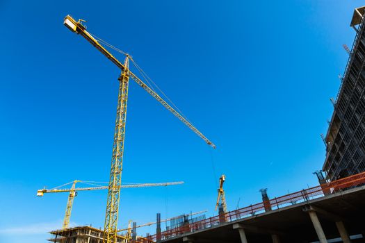 Construction cranes on building site on sky background