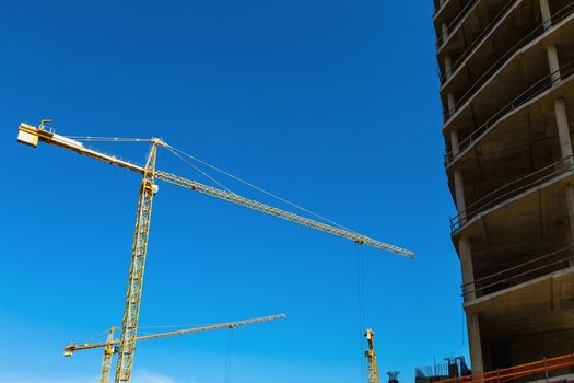 Construction cranes on building site on sky background