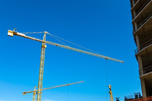 Construction cranes on building site on sky background
