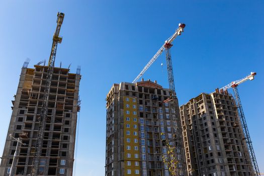 Construction cranes on building site on sky background