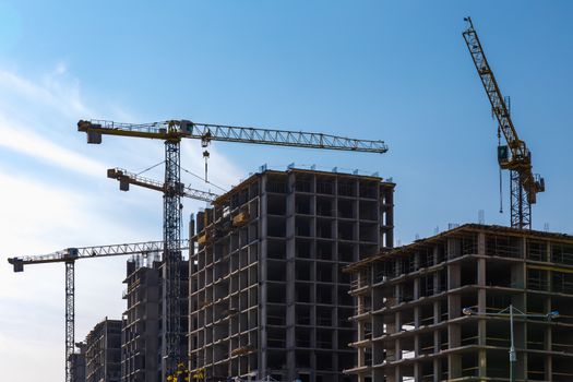 Construction cranes on building site on sky background
