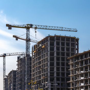 Construction cranes on building site on sky background