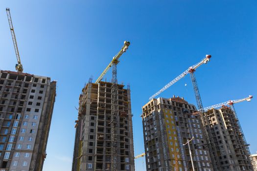 Construction cranes on building site on sky background