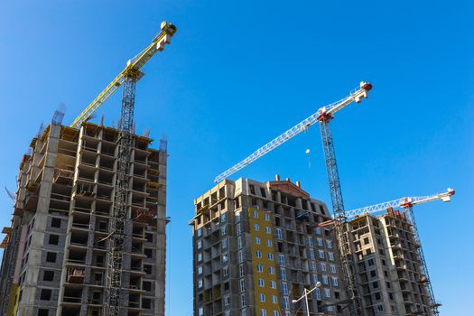Construction cranes on building site on sky background