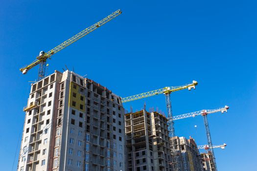 Construction cranes on building site on sky background