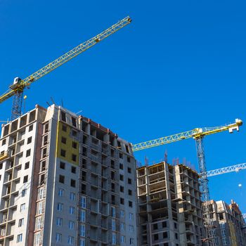Construction cranes on building site on sky background