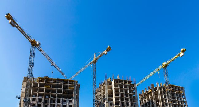Construction cranes on building site on sky background