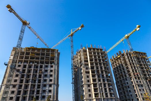 Construction cranes on building site on sky background