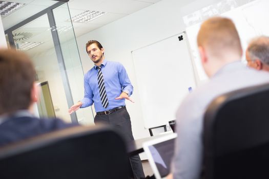 Business man making a presentation at office. Business executive delivering a presentation to his colleagues during meeting or in-house business training, explaining business plans to his employees.