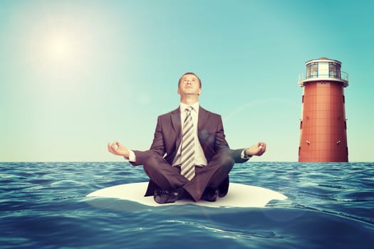 Businessman sitting in lotus position on small island in sea and looking up