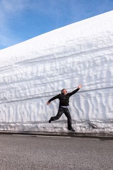 man running on the highway along the snow wall. Norway in the spring