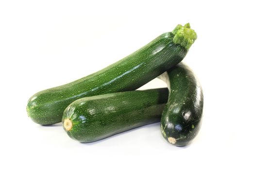 green, raw zucchini in front of white background