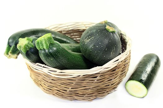 green, raw zucchini in front of white background