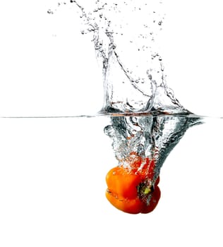 Fresh red pepper drops into a water, isolated on white background