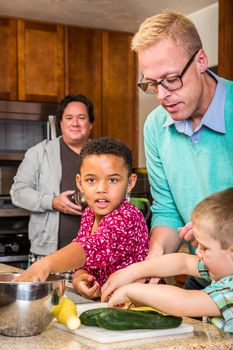 Two dads in kitchen cook with children