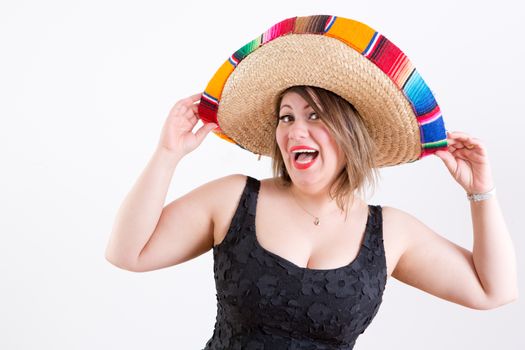 Close up Smiling Lady in Sleeveless Black Shirt with Mexican Sombrero on her Head, Looking at Camera, Emphasizing Welcome to the Party Gesture. Captured Indoor with White Background.