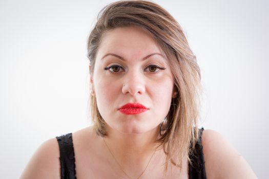 Close up Serious Portrait of a Young Blond Woman with Makeup Staring at the Camera on a Light Gray Background.