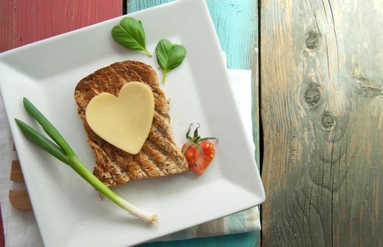 Heart shape slice of cheese on toasted whole grain bread