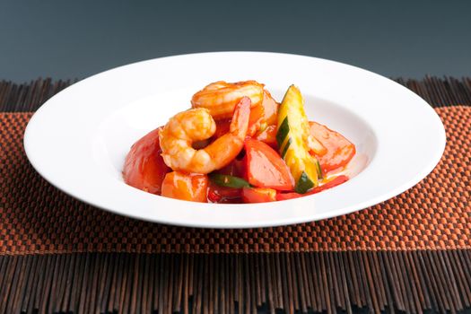 Thai style sweet and sour shrimp dish presented beautifully on a round white plate.