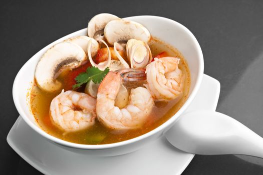 Thai shrimp soup bowl close up with mushrooms and vegetables.