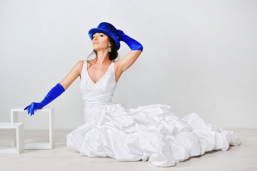 Beautiful girl in a white dress with a blue hat on a white background.