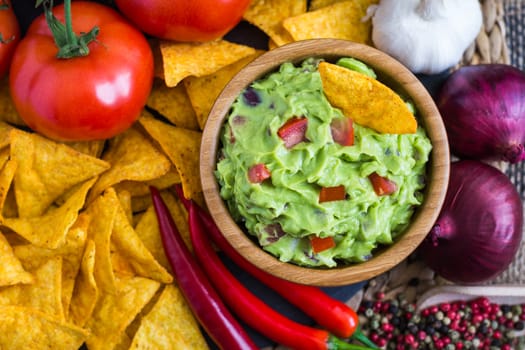 Guacamole in Wooden Bowl with Tortilla Chips and Ingredients