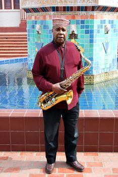 Muslim male jazz musician with his saxophone outdoors.