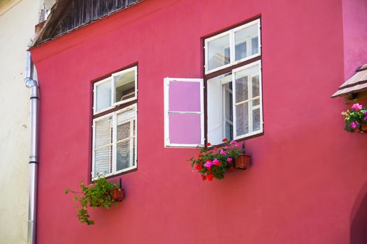 Turda, Romania - June 23, 2013: Pink facade with white windows and street lamp on an old pink house from the Old Turda city center, Romania
