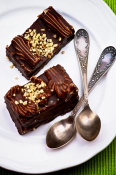 Chocolate Mocha Cakes Mocha Frosting, Cream and Nuts with Silver Tea Spoons closeup on White Plate